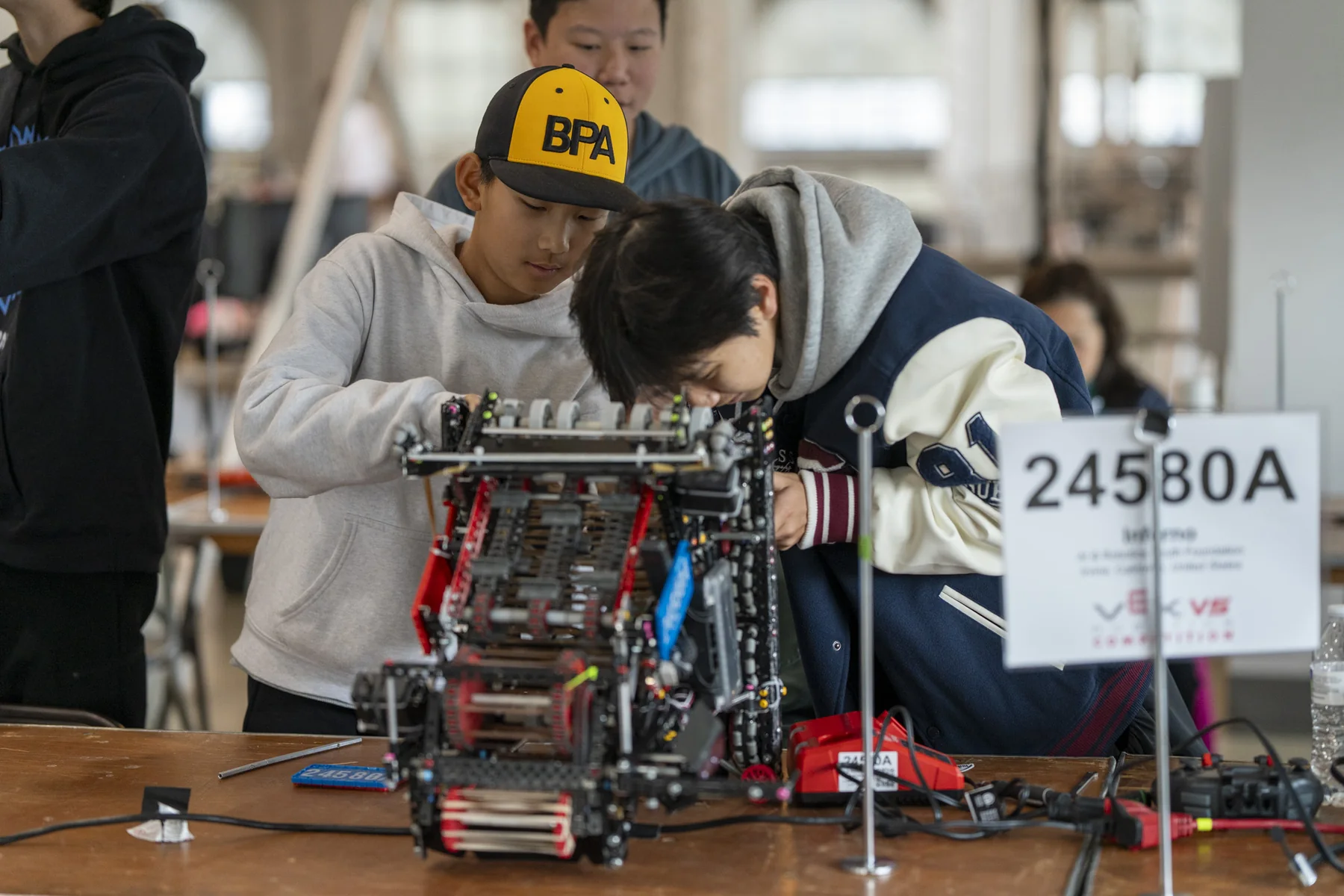 Team 24580A at the bench, working on their robot beside the team placard.