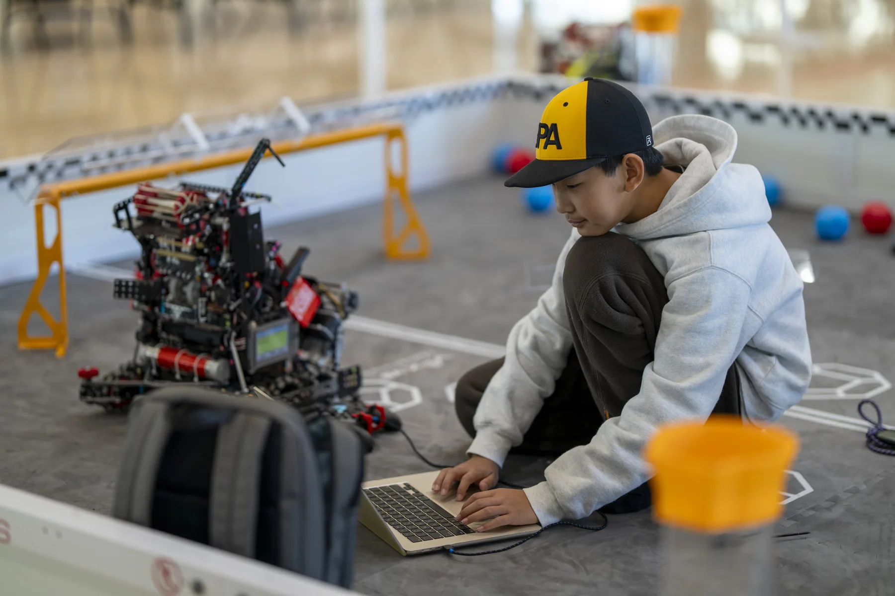 A team member coding the robot at the edge of the competition field.